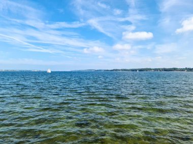 Ufukta, Baltık Denizi 'nin mavi sularında küçük beyaz bir yelkenli gemi.