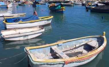 Marsaxlokk, Malta - 29. Eylül 2024: Malta 'daki Marsaxlokk limanında gün ışığında küçük balıkçı teknelerinin görüntüsü