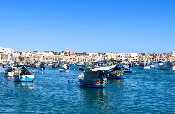 Marsaxlokk, Malta - 29. Eylül 2024: Malta 'daki Marsaxlokk limanında gün ışığında küçük balıkçı teknelerinin görüntüsü