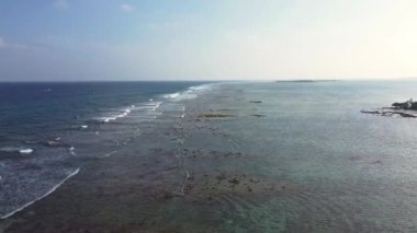 Dalgaların Maldivler 'de dalgalandığı okyanus mavisi ve ufuk manzaralı bir sahilin drone görüntüsü..