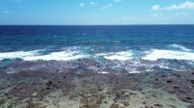Dalgaların Maldivler 'de dalgalandığı okyanus mavisi ve ufuk manzaralı bir sahilin drone görüntüsü..