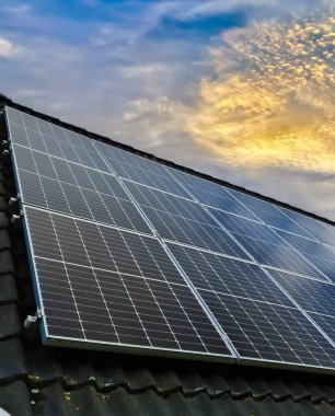 Colorful sunset on solar panels producing clean energy on a roof of a residential house