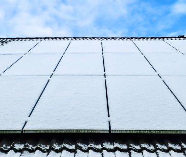 Kar, bir evin çatısında temiz enerji üreten güneş panellerini kapladı