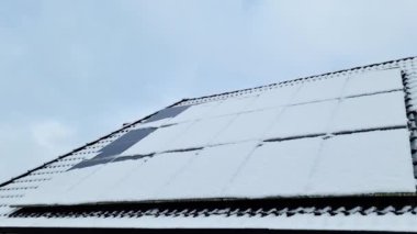 Neredeyse tamamen karla kaplı birçok güneş hücresi olan bir çatı görüntüsü.
