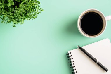 Not defteri kalemi ve bir fincan kahveyle minimalist çalışma alanının en üst görüntüsü