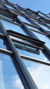 Modern ofis yüzleri cam ve yansıtan güneş ışığı ve bazı bulutlar ile.