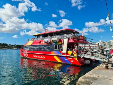 Valletta, Malta 25 Ağustos 2024: Turistler güneşli bir günde Malta 'nın Sliema kentinde gökkuşağı eşliğinde kırmızı feribota biniyorlar