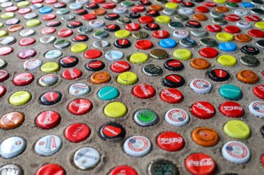 Berlin, Almanya - 03. Ekim 2024: Çimentoya gömülü çok sayıda renkli şişe kapağı Berlin 'de dekoratif bir mozaik yüzeyi oluşturuyor