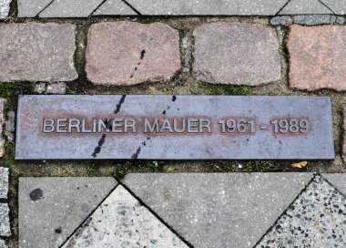 Berlin, Almanya - 03. Ekim 2024: 1961-1989 yılları arasında Berlin Duvarı 'nın anısına asfalta gömülü paslı bir metal plaketin yakın çekim görüntüsü