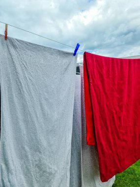 Temiz çamaşırlar, havlular ve battaniyeler, çamaşır ipinde asılı ve bulutlu bir gökyüzünün altında kuruyor.