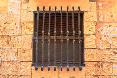 Mdina, Malta 30 Eylül 2024: Mdina, Malta 'da demir parmaklıklı bir penceresi olan yıpranmış taş bir duvar
