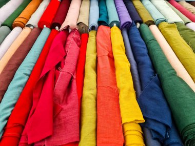 Birçok renkli kumaş bir tekstil dükkanında asılı, çeşitli renk ve dokular sergiliyor, dikiş ve el işi projeleri için mükemmel.