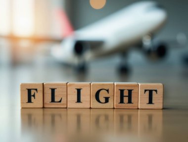 Tahta bloklar arka planda bulanık bir model uçak ile kelime uçuşu, seyahat ve havacılık çağrıştıran