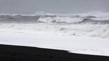 Güçlü okyanus dalgaları İzlanda 'daki Reynisfjara kara kumsalına çarpıyor.