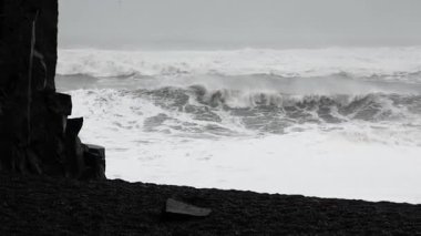 Güçlü okyanus dalgaları İzlanda 'daki Reynisfjara kara kumsalına çarpıyor.