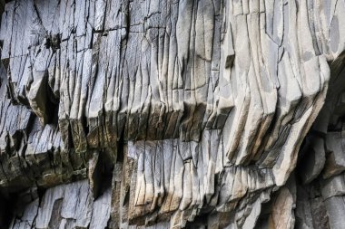 Bazalt kaya oluşumlarının yakın görüntüsü karmaşık desenler ve dokular sergiliyor, İzlanda 'nın jeolojik harikalarını vurguluyor