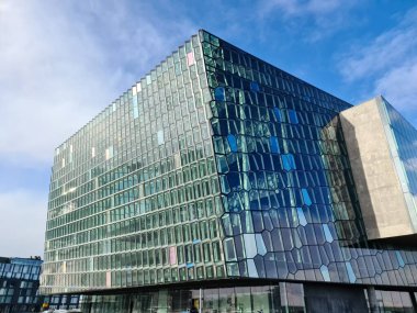 Reykjavik, İzlanda - 05. Mart 2025: Harpa Konser Salonu 'nun modern cam cephesi, İzlanda' nın Reykjavik kentindeki mavi gökyüzünü yansıtıyor.