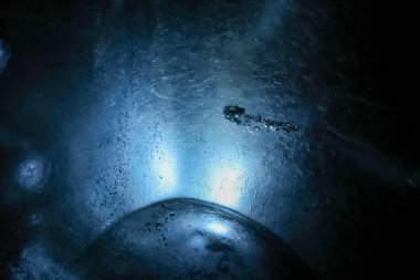 Buzun içinden süzülen ışık, Vatnajokull Buzulu, İzlanda 'daki bir buz mağarasında büyüleyici bir mavi parıltı yaratır.