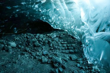 Çarpıcı turkuaz buz oluşumları, Vatnajokull buzulu, İzlanda 'daki bir buz mağarasında yere saçılmış kayalarla büyüleyici bir manzara yaratır.