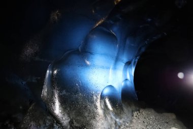 Buz mağarasının içini aydınlatan ışık, İzlanda 'daki vatnajokull buzulu içindeki doğal mavi buz oluşumlarını gösteriyor.