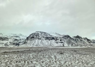 Sersemletici kar tozlu dağlar İzlanda topraklarına hükmediyor, kışın doğanın saf güzelliğini sergiliyor.