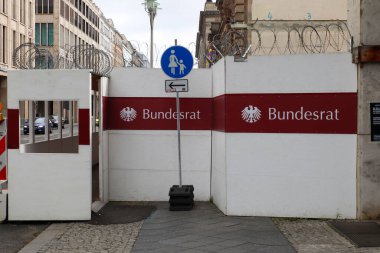 Berlin, Almanya 03. Ekim 2024, Berlin 'deki Bundesrat binasını koruyan dikenli teller, yürüme yolunu gösteren bir yaya tabelası var.