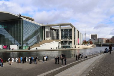 Berlin, Almanya 03. Ekim 2024, Berlin 'deki Alman parlamento kütüphanesine ev sahipliği yapan Marie Elisabeth Luders Haus yakınlarında Spree Nehri boyunca yürüyen turistler