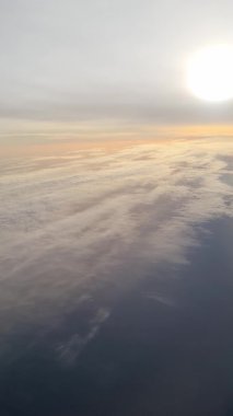 Hava görüntüsü, stratosferik manzara üzerinde sakin yüksek irtifa uçuşları sırasında sıcak günbatımı renkleriyle parlayan katmanlı bulutları ortaya çıkarıyor.