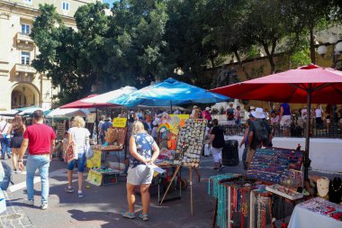 Valletta, Malta 27. Eylül 2024, insanlar güneşli bir yaz gününde Malta 'nın Valletta kentindeki Yukarı Barrakka Bahçeleri' nde kalabalık bir açık hava pazarında yürüyüş ve alışveriş yapıyorlar.