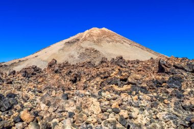 Volkanik manzarada katı lav kayaları ve Teide Dağı volkanı Tenerife, Kanarya Adaları, İspanya 'da güneşli bir günde yükseliyor.