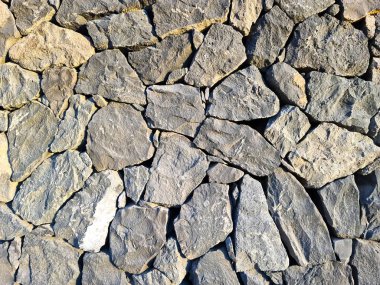 Kaba bir taş duvarı aydınlatan güneş ışığı, mimari ve inşaat projeleri için ideal dokulu bir zemin oluşturuyor.