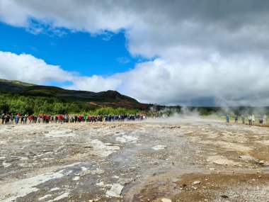 Haukadalur, İzlanda 22. Haziran 2024, İzlanda 'nın Haukadalur vadisinde Strokkur gayzerinin bir sonraki patlamasını bekleyen turistler