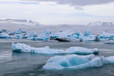 İzlanda 'da Jokulsarlon buzulunda yüzen buzdağları ve arka planda Vatnajokull buzulları
