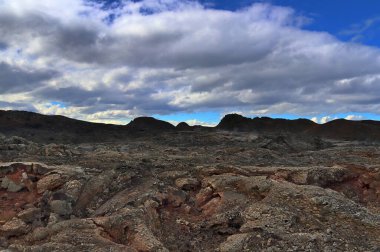 Volkanik manzarada İzlanda 'da büyük bir lav sahası, dramatik ve bulutlu gökyüzünün zemininde buhar salıyor.