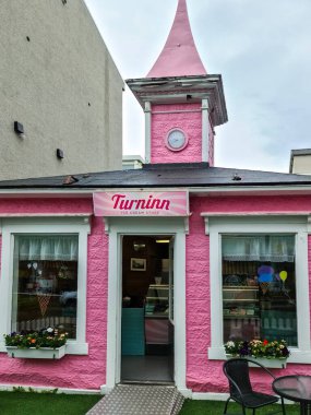 İzlanda, Akureyri 22. Haziran 2024, Akureyri, İzlanda 'daki Turninn Dondurmacısı canlı pembe dış görünüşü, büyüleyici saat kulesi ve hoş geldin girişi ile göze çarpıyor.