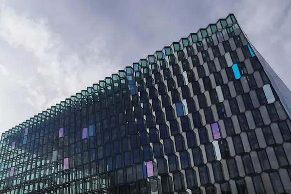 Harpa Konser Salonu 'nun modern cam cephesi Reykjavik, İzlanda' daki dinamik ve bulutlu gökyüzünü yansıtıyor.