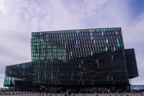 Harpa Konser Salonu 'nun modern cam cephesi Reykjavik, İzlanda' daki bulutlu gökyüzünü yansıtıyor ve eşsiz mimarisini gözler önüne seriyor.