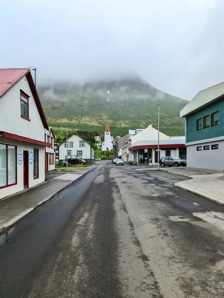 İzlanda, Akureyri 22. Haziran 2024, Akureyri 'de Islak Sokak. Akureyrarkirkja Kilisesi' ne açılıyor. Görkemli Sulur Dağı arka planda bulutlarla kaplı.