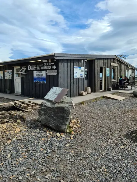 Hofn, İzlanda 22. Haziran 2024, İzlanda, Hofn 'daki Viking Köyü' nün küçük ahşap bilet ofisi, dinlenen turistler ve güzel bulutlu gökyüzü