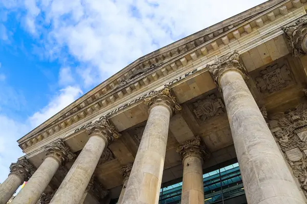 Berlin, Almanya 'da mavi gökyüzü altında sütunlar, yazıtlar ve süslü detaylarla Reichstag binasının ön cephesinin düşük açılı görüntüsü