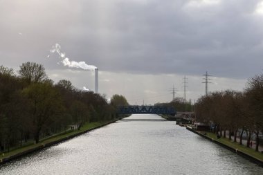 Oberhausen, Almanya - 30. Mart 2025: Oberhausen, Almanya 'da baca, köprü ve elektrik direkleriyle Ren-Herne Kanalı' nı gösteren sanayi manzarası