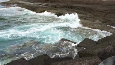 Turkuaz okyanus dalgaları, İspanya 'nın Kanarya Adaları' ndaki kayalık Tenerife kıyı şeridi boyunca beyaz sprey püskürtüyor.