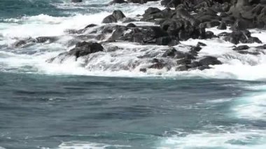 Turkuaz okyanus dalgaları İspanya 'nın Kanarya Adaları, Tenerife sahilindeki siyah volkanik kayalara çarpıyor.