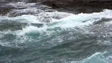 Güçlü okyanus dalgaları sert bir şekilde engebeli Tenerife kıyı şeridi boyunca uzanan karanlık volkanik kayalara çarpıyor, doğal deniz enerjisi ve dramatik deniz manzarası sergiliyor.