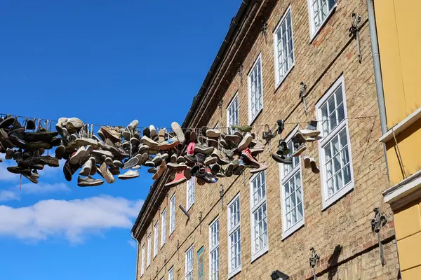 Flensburg, Almanya 'nın tarihi şehir merkezinde, arka planda mavi gökyüzü olan bir telden sarkan spor ayakkabı ve ayakkabılar.