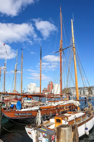 Direkleri ile tahta yelkenli tekneler güneşli bir bahar gününde Almanya 'nın Flensburg limanında sakin bir manzara yaratıyor.