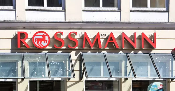 Almanya 'nın Flensburg kentindeki bir dükkanın cam güneşliğinin üzerinde at ve binicinin sembolü parlayan kırmızı Rossmann logosu.