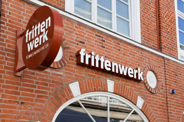 Frittenwerk tabelasının yakın çekimleri kırmızı tuğlalı bir binada sergileniyor, Flensburg 'da markanın kimliğini gösteriyor.