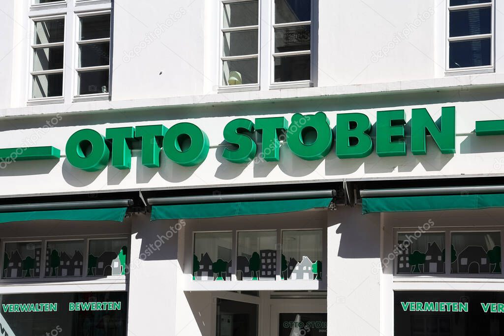 Green Otto Stoben logo on a white building facade in Flensburg, Germany, offering real estate services such as renting, managing, and evaluating properties