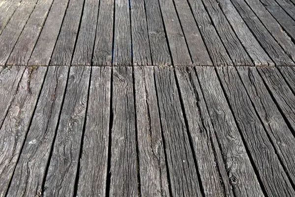 Paralel yıpranmış ahşap kalaslar, yaş ve elementlere maruz kalma belirtileri gösteren dokulu bir yüzey oluşturur.